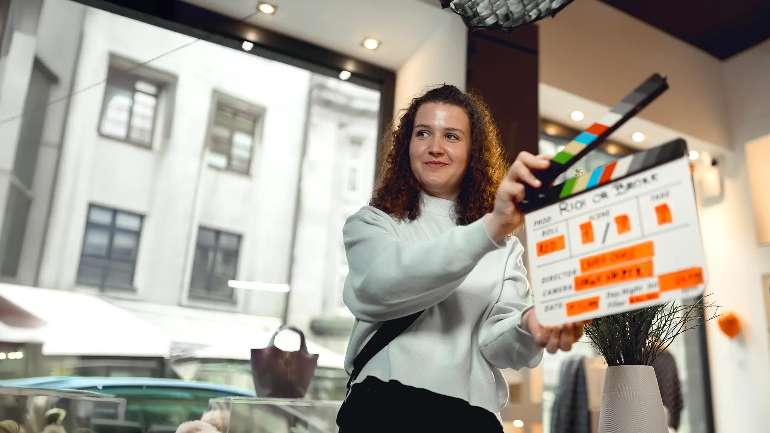 Schülerin hält eine Filmklappe während der Dreharbeiten in einem Innenraum