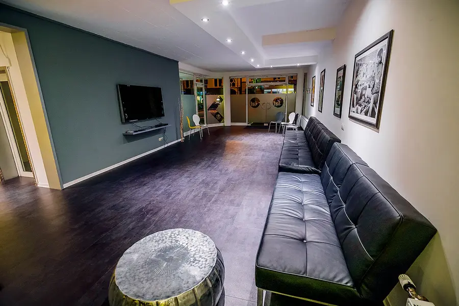 Lounge der Akademie mit langem Ledersofa, Fernseher und gerahmten Fotos