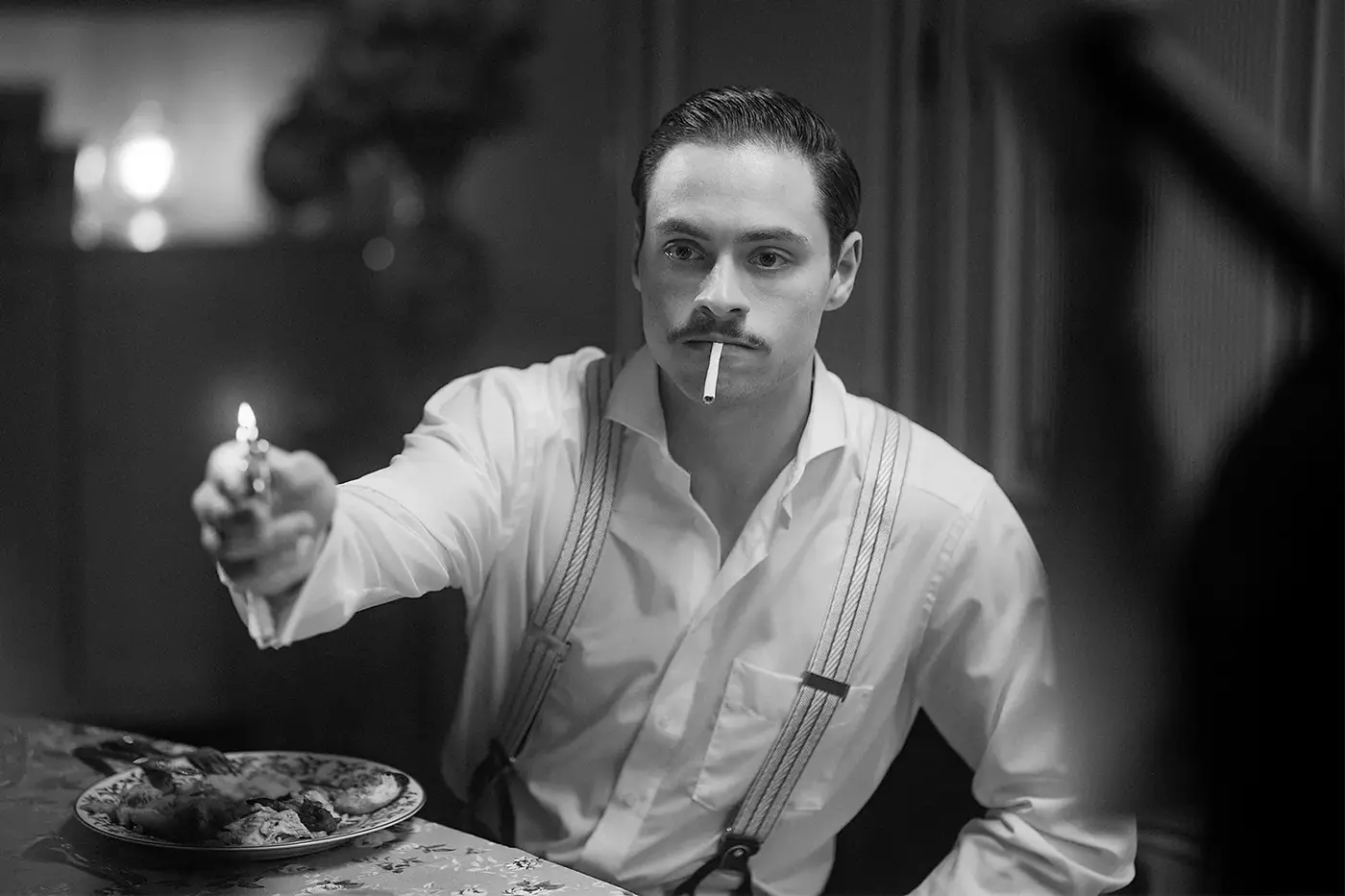 Schwarz-weiße Filmnoir-Szene, Mann mit Schnurrbart zündet sich am Tisch eine Zigarette an, Standbild aus dem IAF Abschlussfilm SW 2025