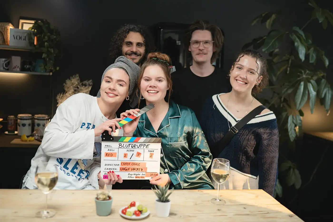 Zwei lachende Darstellerinnen hinter einer Filmklappe am Set, Standbild aus dem IAF Abschlussfilm Blutgruppe Schwester 2025