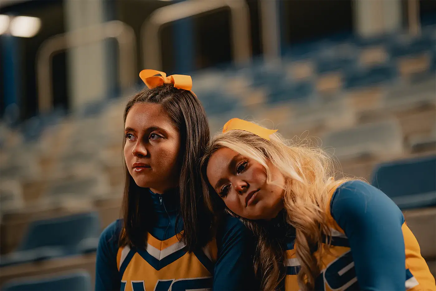 Zwei Cheerleaderinnen in blau-gelben Uniformen auf der Stadiontribüne, Standbild aus dem IAF Abschlussfilm Cheerleader 2025
